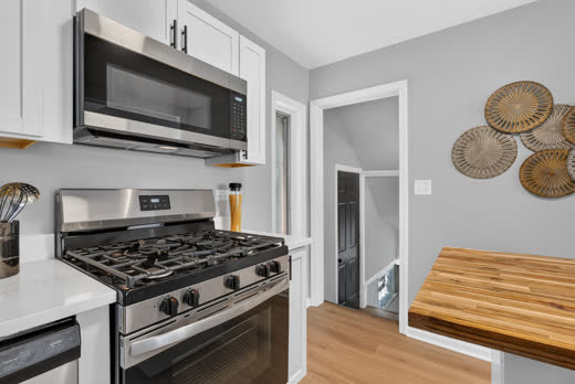 Stainless gas range and microwave detail in renovated kitchen, 9205 S Utica Ave