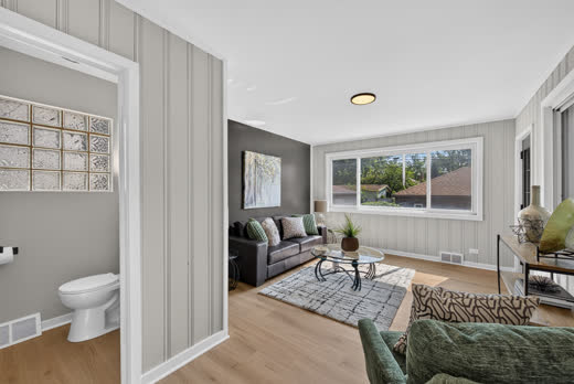 Staged living room with accent wall and large window at 9205 S Utica Ave
