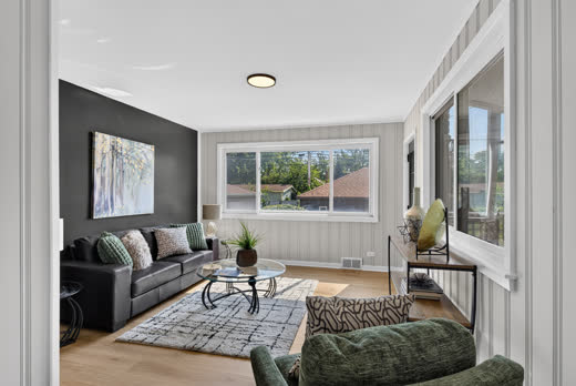 Bright living room with charcoal accent wall and large windows, 9205 S Utica Ave
