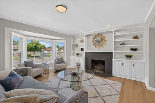 Staged living room with fireplace, white built-ins, and bay window in renovated Evergreen Park home