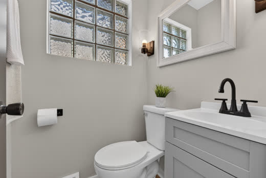 Updated bathroom with gray vanity, matte black faucet and glass block window at 9205 S Utica Ave