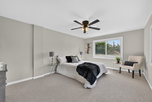 Spacious primary bedroom with ceiling fan and large window at 9205 S Utica Ave