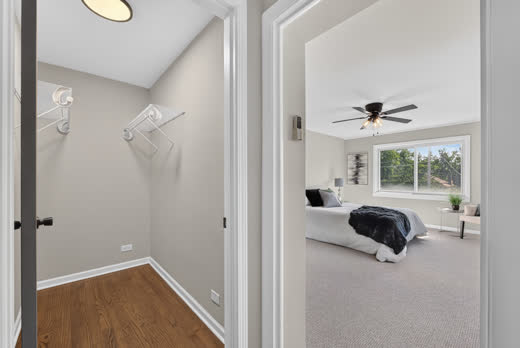 Walk-in closet with hardwood floor adjoining primary bedroom at 9205 S Utica Ave