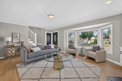 Sunlit living room with bay window and staircase at 9205 S Utica Ave, Evergreen Park