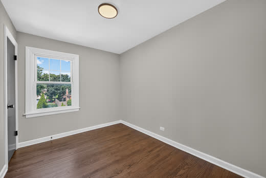 Bedroom with refinished hardwood floors and sunny window in Evergreen Park home