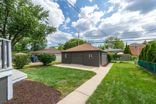 Fenced backyard with green lawn and detached garage at 9205 S Utica Ave, Evergreen Park