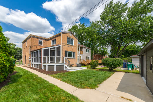 Rear exterior of brick two-story home with screened porch at 9205 S Utica Ave